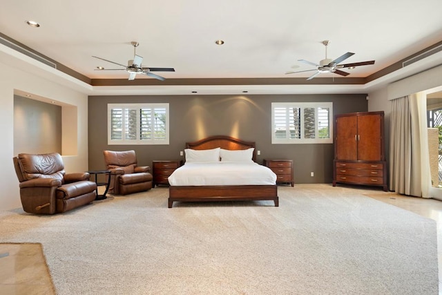 bedroom featuring a tray ceiling, multiple windows, and ceiling fan