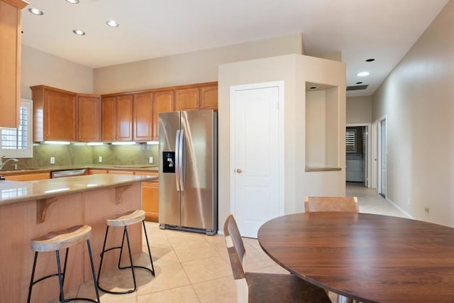 kitchen with backsplash, sink, light tile patterned flooring, and appliances with stainless steel finishes