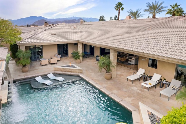 rear view of property with a patio area, a mountain view, and an outdoor fire pit