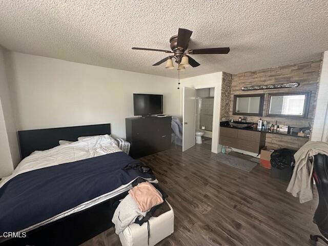 bedroom with a textured ceiling, ceiling fan, and dark wood-type flooring