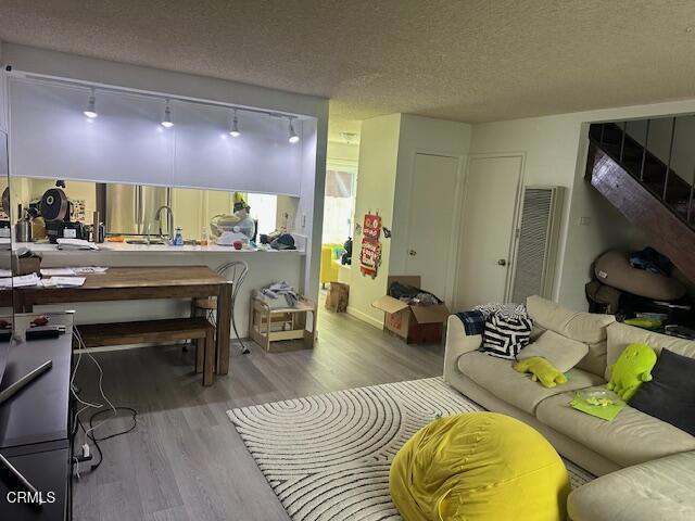 living room with a textured ceiling, track lighting, and light wood-type flooring