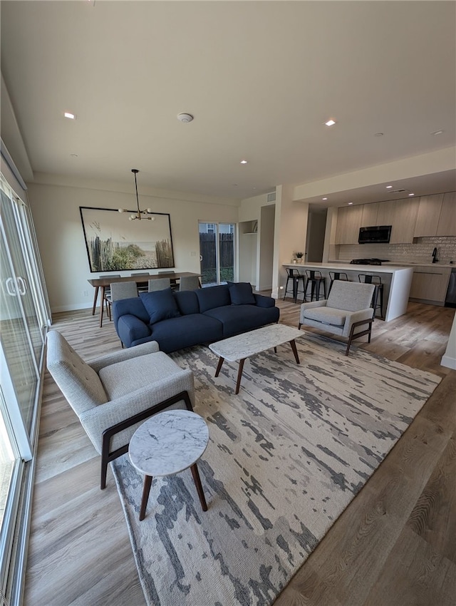 living room featuring crown molding, light hardwood / wood-style floors, and a notable chandelier