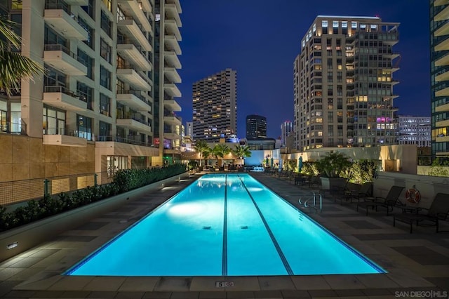 pool at night featuring a patio area