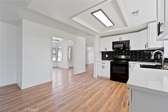 kitchen with white cabinets, black appliances, and light wood-type flooring