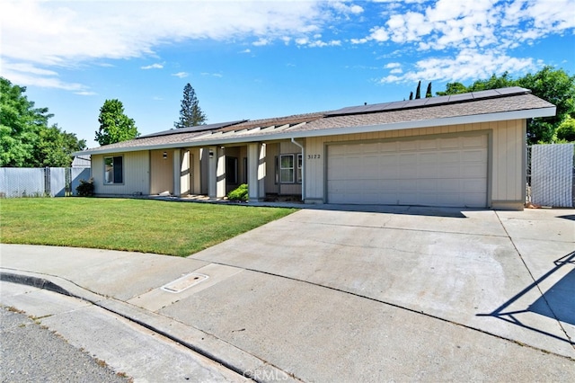 ranch-style home with solar panels, a garage, and a front yard