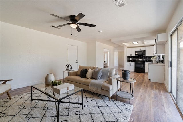 living room with hardwood / wood-style flooring, ceiling fan, and sink