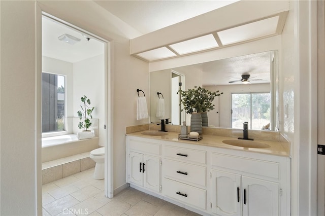 bathroom featuring ceiling fan, a relaxing tiled tub, tile patterned floors, toilet, and vanity