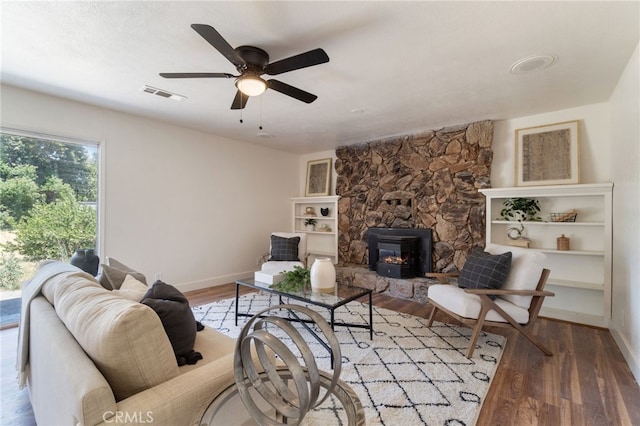 living room featuring a wood stove, ceiling fan, and hardwood / wood-style floors