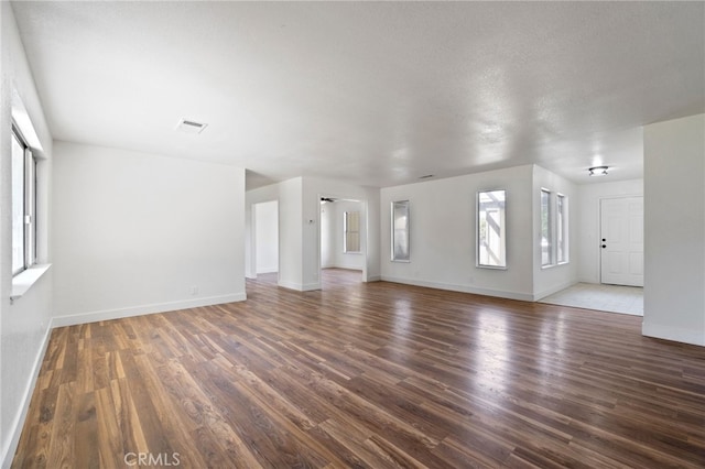 unfurnished living room with dark wood-type flooring and a textured ceiling