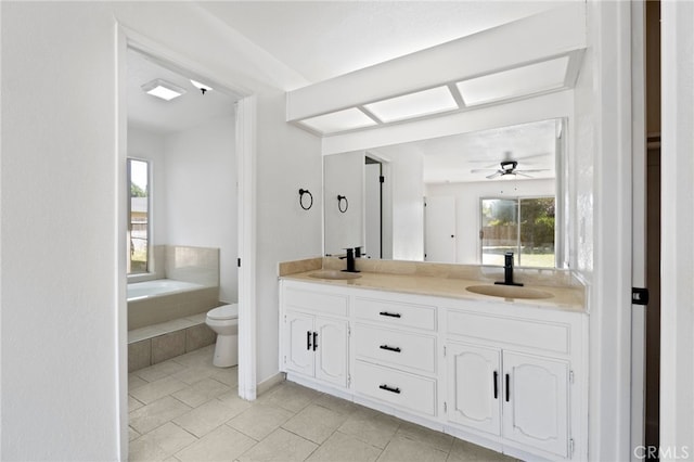 bathroom featuring vanity, ceiling fan, tiled tub, tile patterned flooring, and toilet