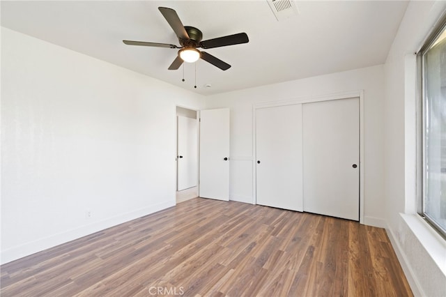 unfurnished bedroom with a closet, ceiling fan, and dark wood-type flooring