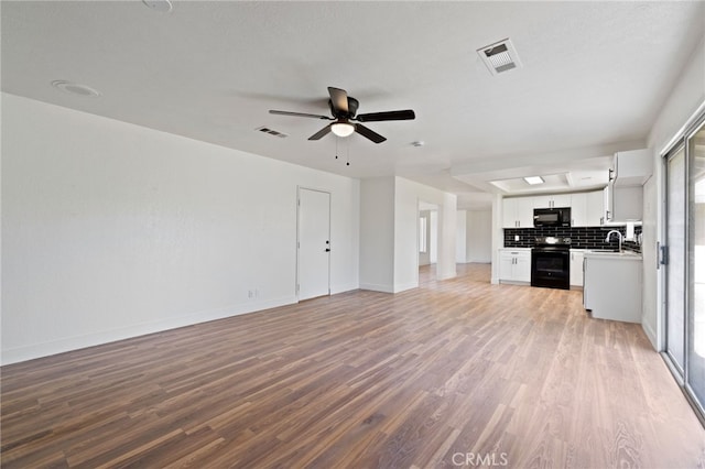 unfurnished living room with ceiling fan, sink, light hardwood / wood-style floors, and a textured ceiling