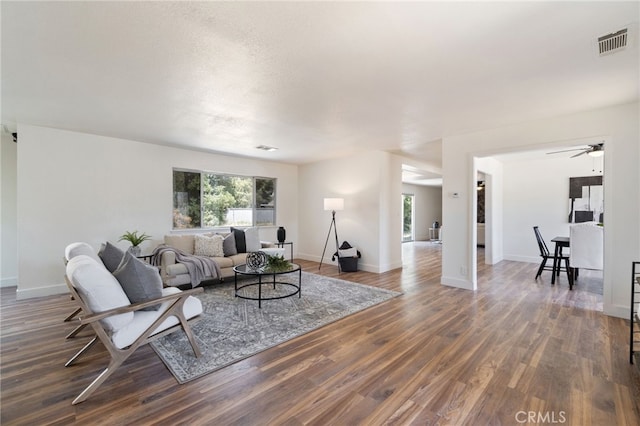 living room with dark hardwood / wood-style flooring and ceiling fan