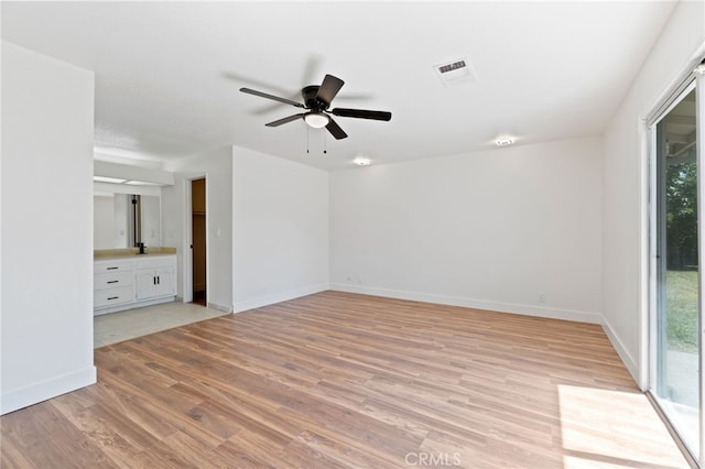 empty room featuring ceiling fan, plenty of natural light, and light wood-type flooring