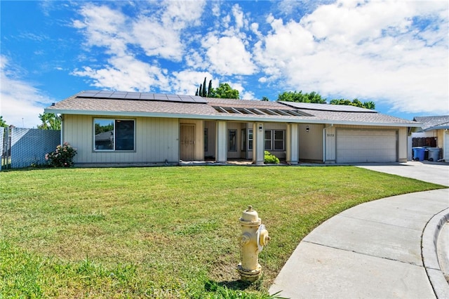 ranch-style home with a garage, a front yard, and solar panels