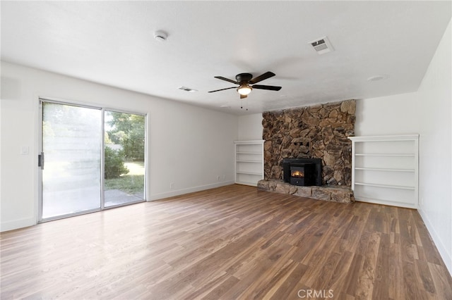 unfurnished living room featuring a wood stove, ceiling fan, and hardwood / wood-style floors