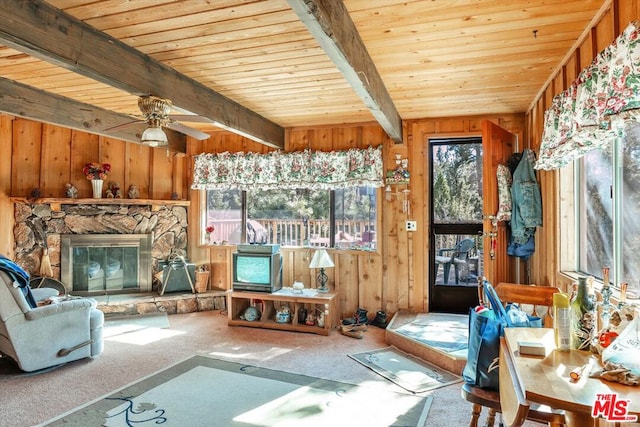 unfurnished sunroom with beam ceiling, ceiling fan, a fireplace, and wooden ceiling