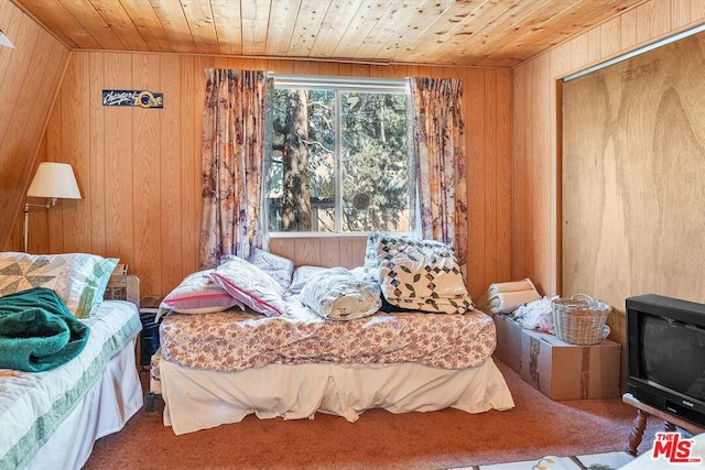 bedroom featuring carpet, a closet, wooden walls, and wood ceiling