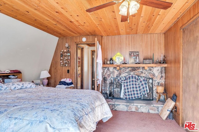 bedroom with ceiling fan, carpet floors, vaulted ceiling, a fireplace, and wood ceiling