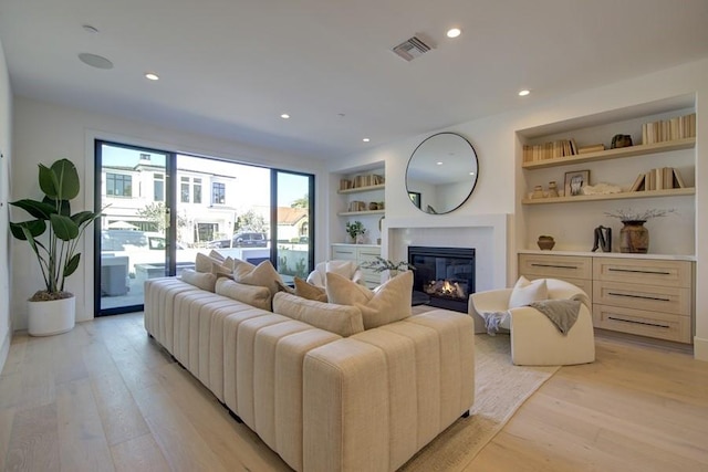 living room featuring built in features and light hardwood / wood-style flooring