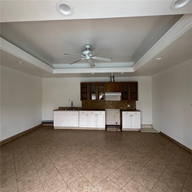 unfurnished living room with ceiling fan, a raised ceiling, ornamental molding, and sink