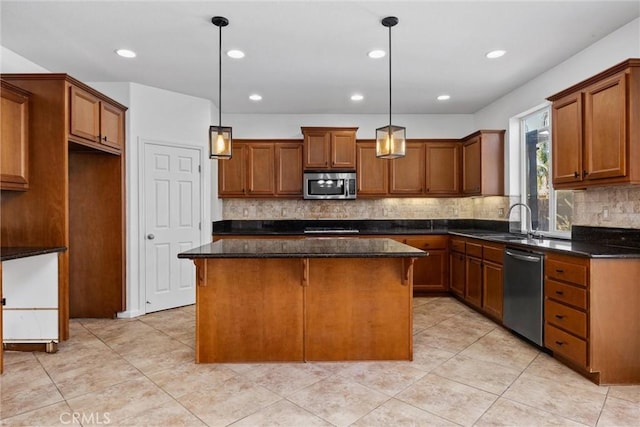 kitchen featuring backsplash, stainless steel appliances, sink, decorative light fixtures, and a kitchen island