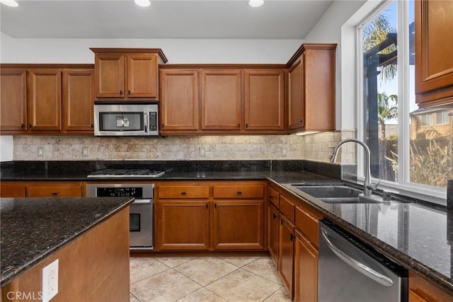 kitchen with appliances with stainless steel finishes, tasteful backsplash, dark stone counters, and sink