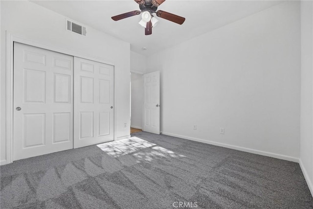 unfurnished bedroom with a closet, dark carpet, and ceiling fan