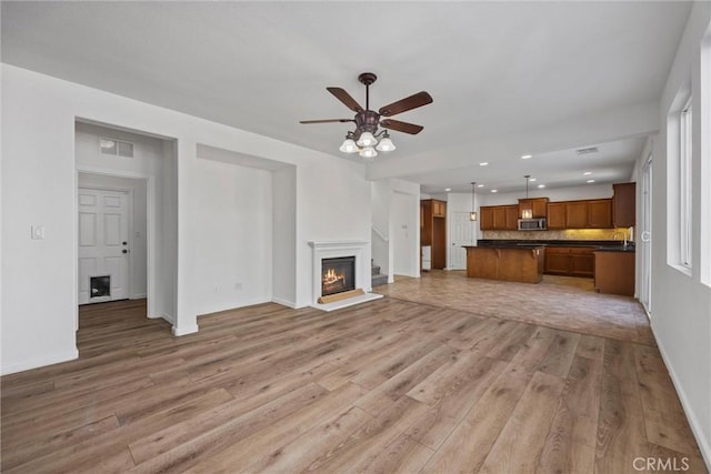 unfurnished living room with ceiling fan and light hardwood / wood-style flooring