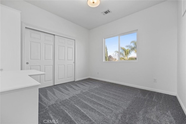 unfurnished bedroom featuring dark colored carpet and a closet