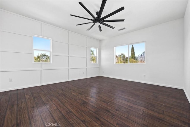 empty room featuring dark hardwood / wood-style flooring, a wealth of natural light, and ceiling fan