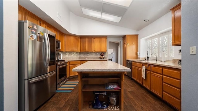 kitchen with sink, dark hardwood / wood-style flooring, vaulted ceiling, a kitchen island, and appliances with stainless steel finishes