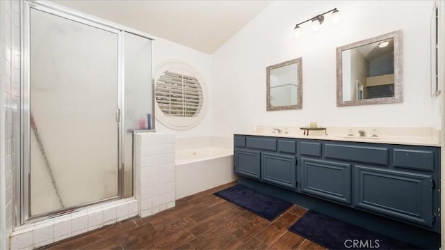 bathroom with wood-type flooring, vanity, vaulted ceiling, and independent shower and bath