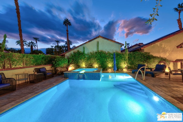 pool at dusk with an in ground hot tub and a patio area