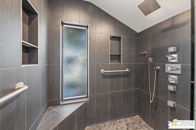 bathroom with a tile shower, a textured ceiling, and lofted ceiling