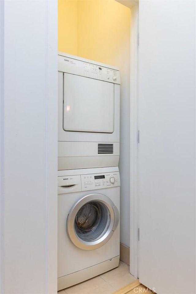 washroom with stacked washer and dryer and light tile patterned flooring