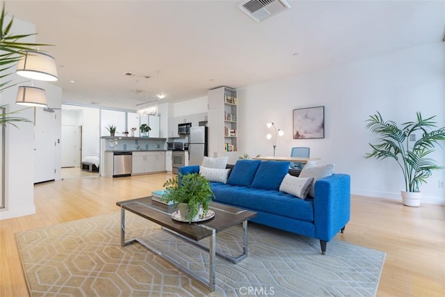 living room with light hardwood / wood-style flooring and a chandelier