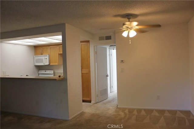 kitchen featuring light brown cabinets, white appliances, ceiling fan, a textured ceiling, and light colored carpet