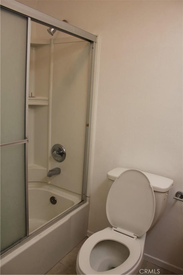 bathroom featuring tile patterned floors, toilet, and bath / shower combo with glass door