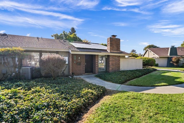 ranch-style house featuring central AC, a front yard, and solar panels