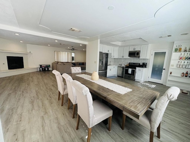 dining room featuring a tray ceiling, ceiling fan, and light wood-type flooring