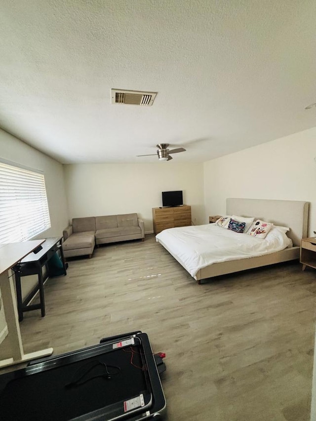 bedroom featuring hardwood / wood-style floors, ceiling fan, and a textured ceiling