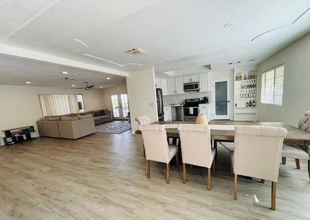 dining space with ceiling fan, light wood-type flooring, and french doors