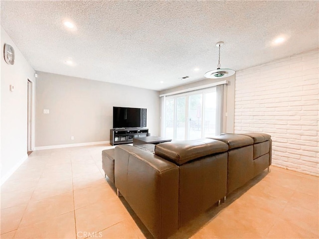 living room with light tile patterned flooring, brick wall, and a textured ceiling