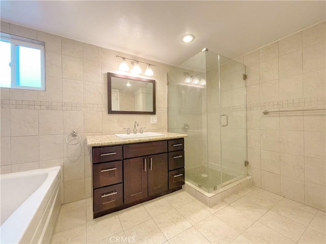 bathroom featuring plus walk in shower, vanity, tile patterned floors, and tile walls