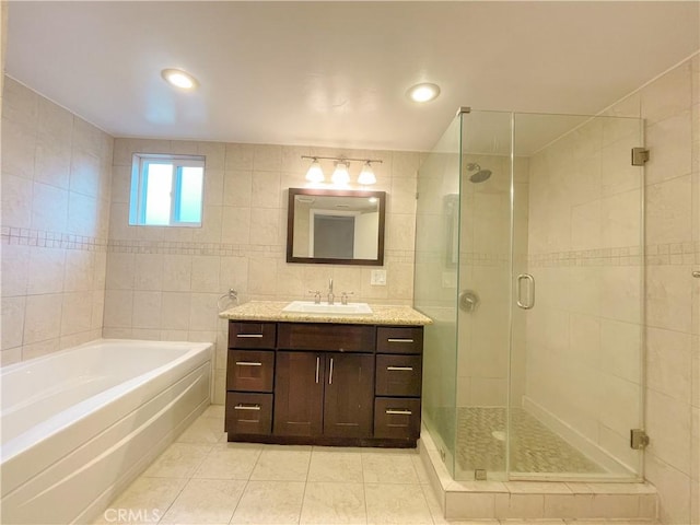 bathroom with tile patterned flooring, vanity, independent shower and bath, and tile walls