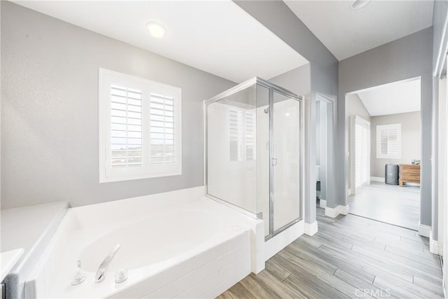 bathroom featuring plus walk in shower and wood-type flooring