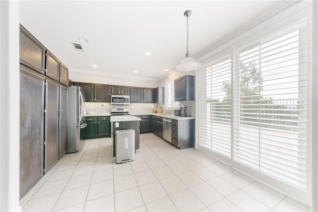 kitchen featuring backsplash, stainless steel appliances, pendant lighting, a kitchen island, and light tile patterned flooring