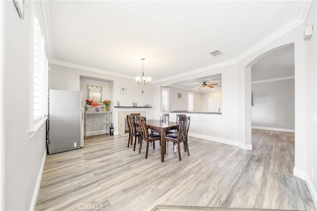 dining area with light hardwood / wood-style flooring, crown molding, and ceiling fan with notable chandelier