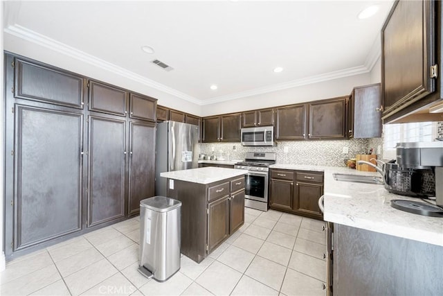 kitchen with sink, stainless steel appliances, ornamental molding, and a center island